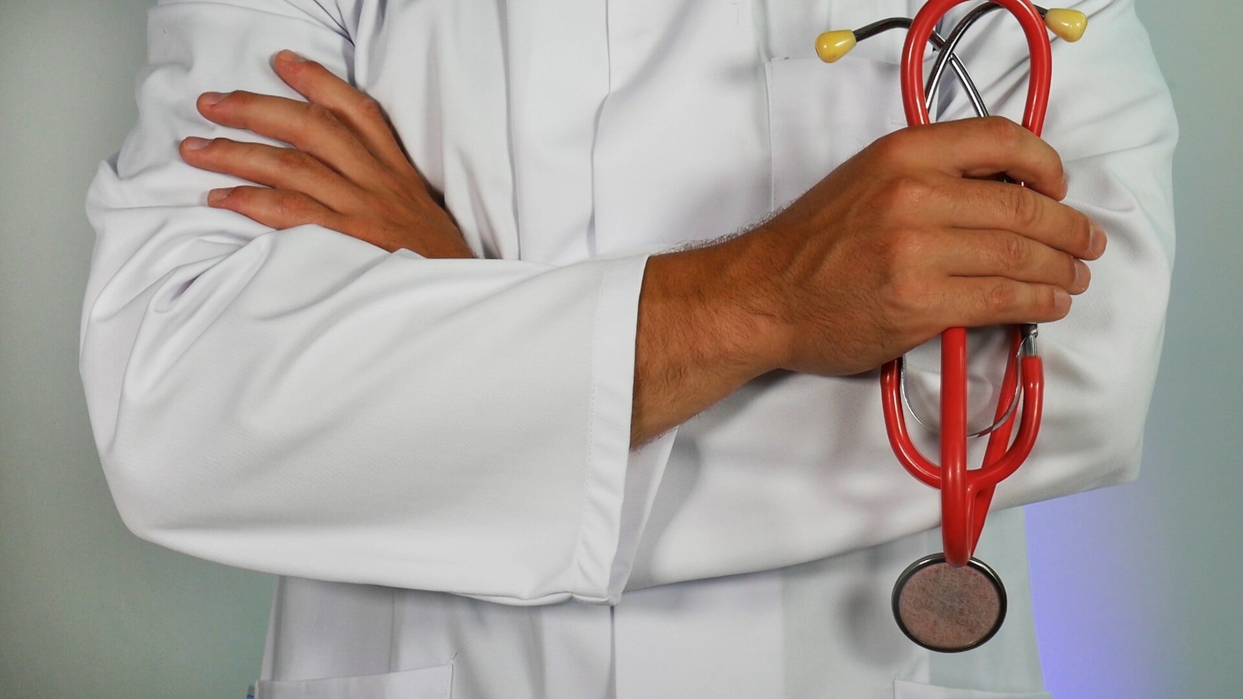 A person in a white doctor's coat holding a stethoscope.